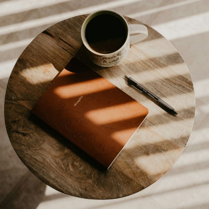 notebook and coffee on sidetable